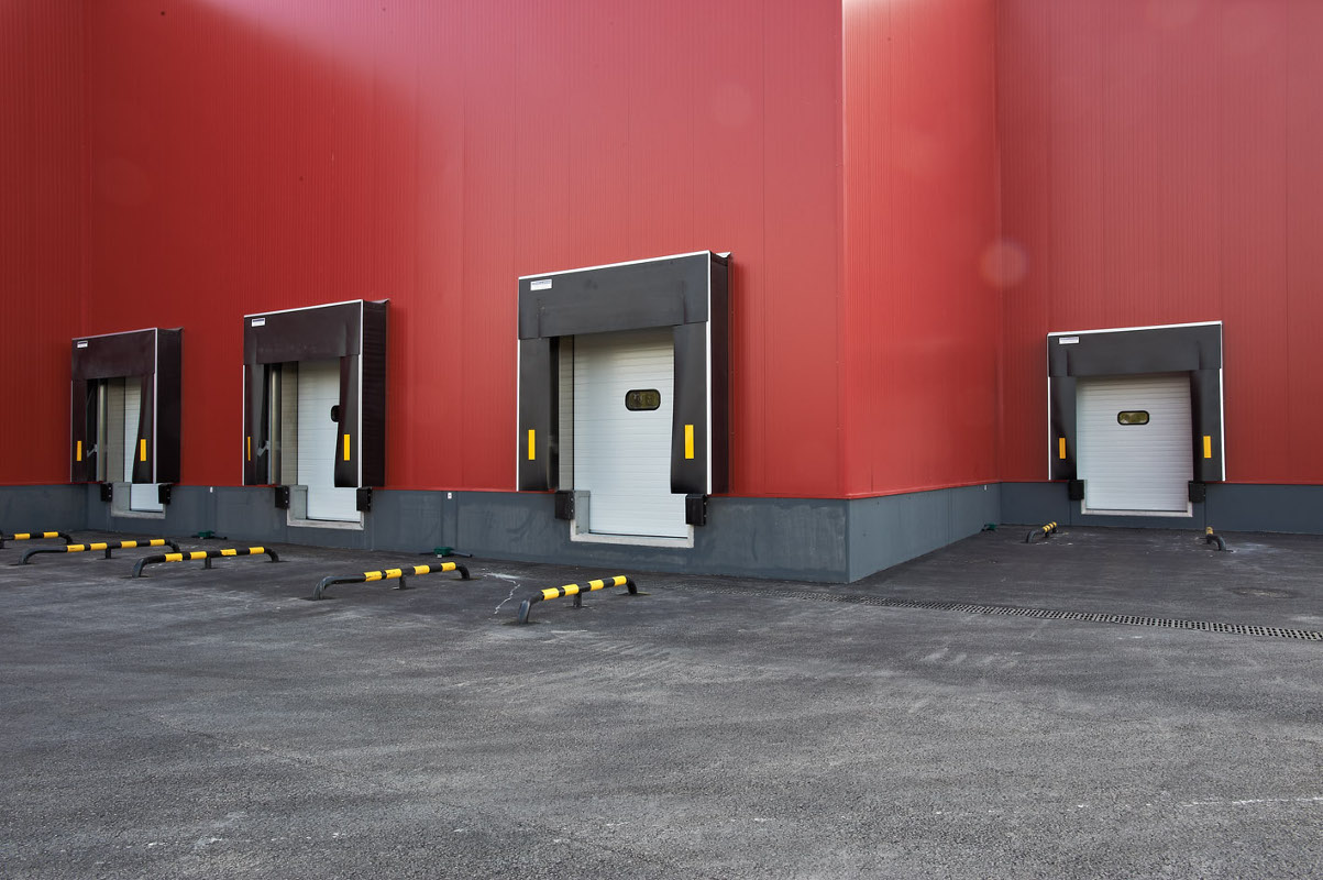 Muelle de carga con rampa retráctil, puerta seccional, abrigo flexible y topes móviles reforzados.